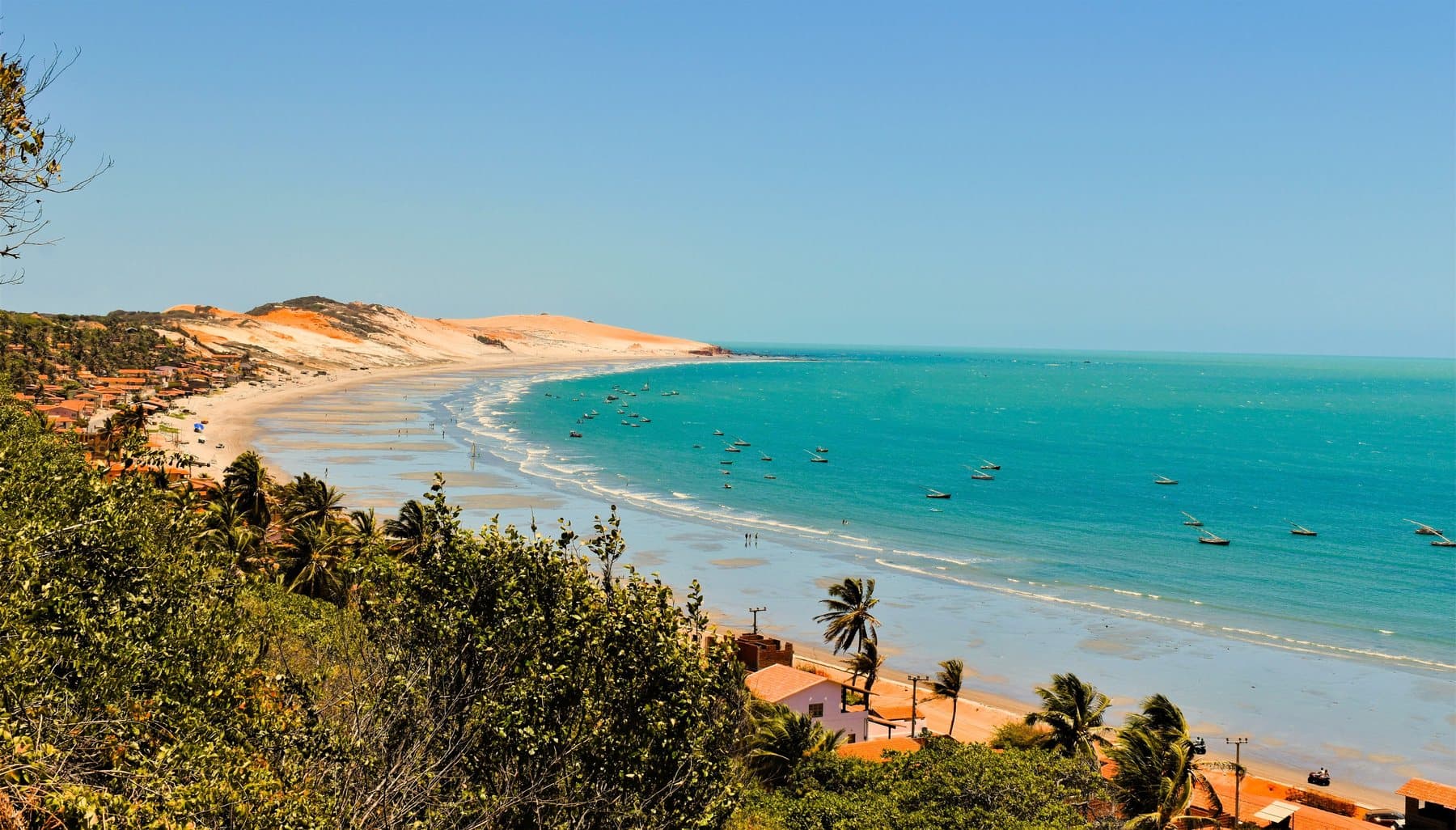 Dunas e mar de água turquesa no litoral do Nordeste brasileiro.