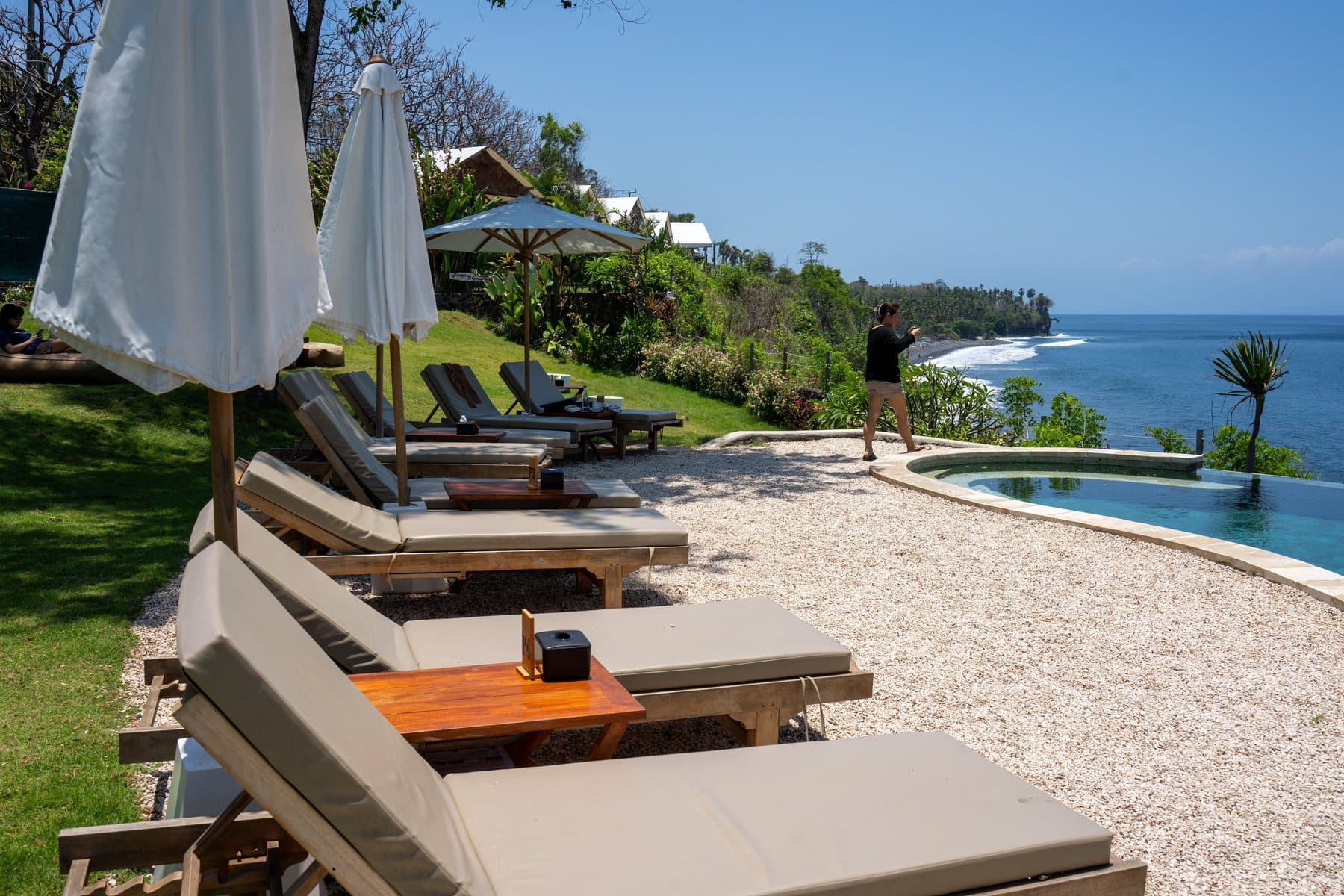 Espreguiçadeiras, piscina e mar em um resort de praia.