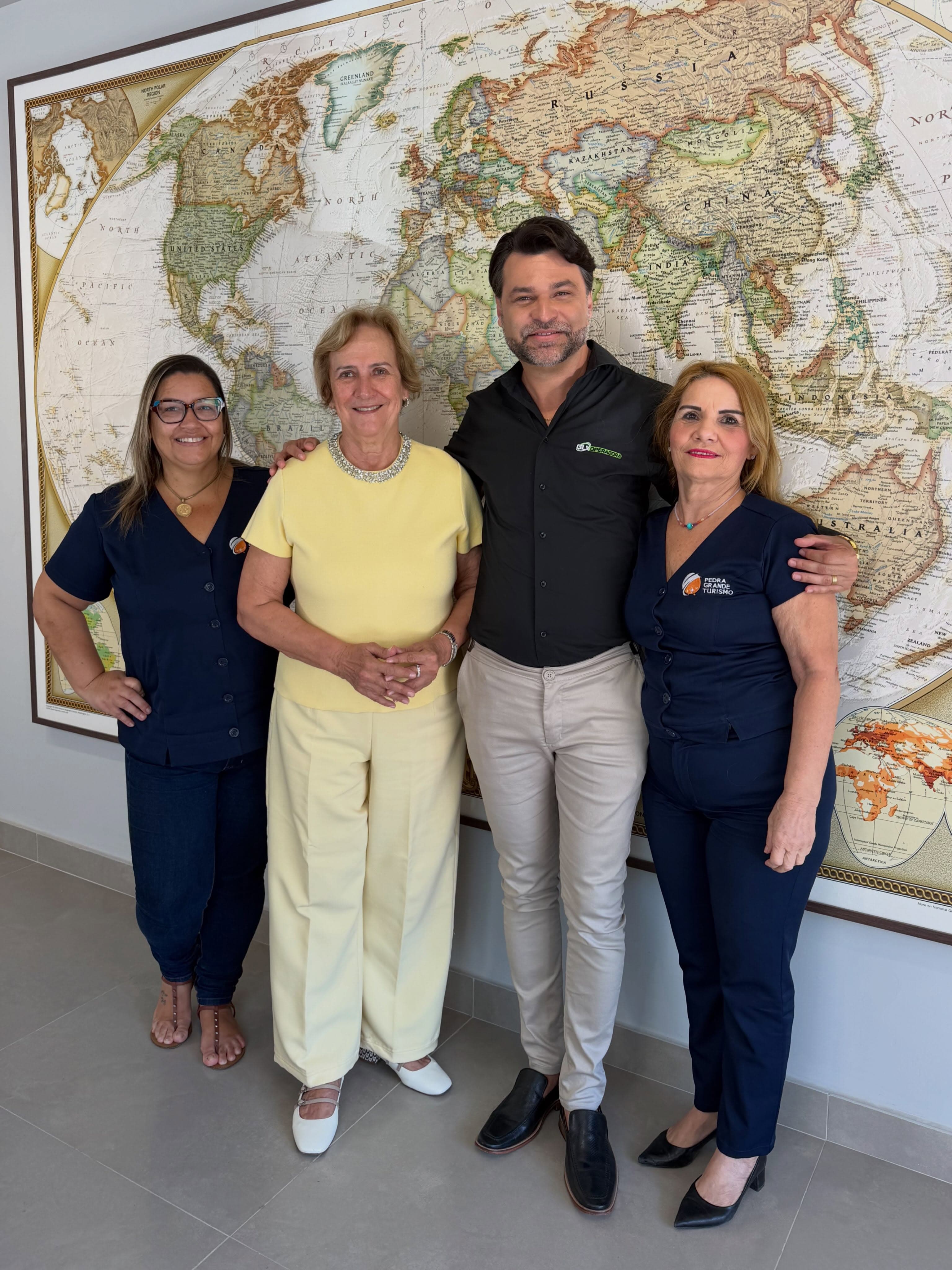 A equipe da Pedra Grande Turismo na loja, em frente ao mapa-múndi.